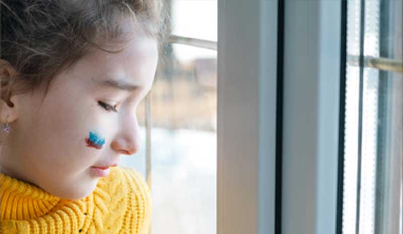 Criança olhando pela janela com expressão introspectiva, representando o impacto emocional das decisões judiciais no desenvolvimento infantil