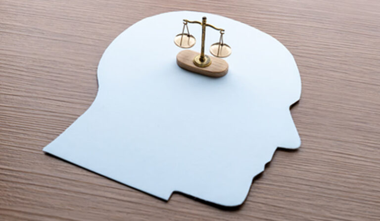 Representação da perícia psicológica judicial, com silhueta de cabeça humana e balança da justiça simbolizando a integração entre Psicologia e Direito, conceito utilizado pela Valente Perícias.