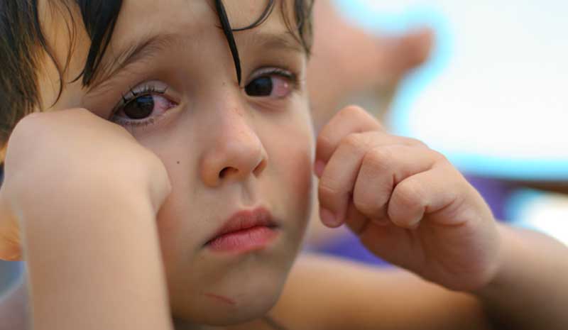 Menino com aparência triste após chorar, em foco estreito, representando impacto emocional infantil em situações de conflito familiar | Valente Perícias